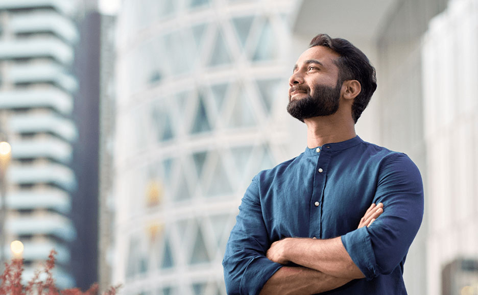 Mann mit verschränkten Armen, der in die Ferne sieht, lächelnd