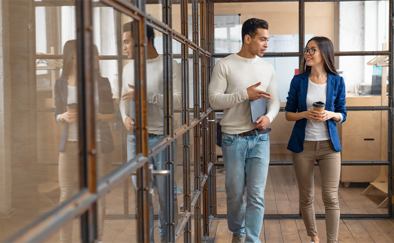 A man and woman walking and discussing a project in an office building