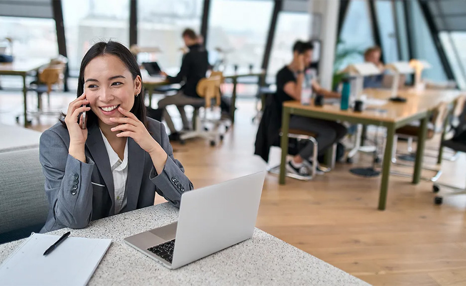  Young Asian business woman talking on mobile phone in big modern office