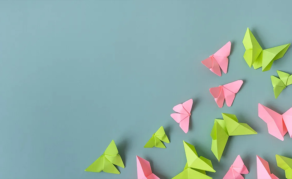 Rosa und grüne Origami-Schmetterlinge auf hellblauem Hintergrund