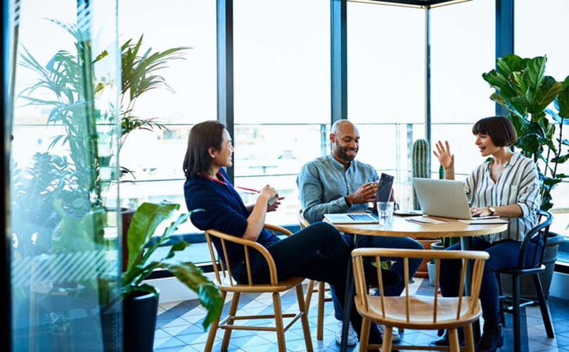 A group of three people at a table, focused on their laptops, working together on a project.