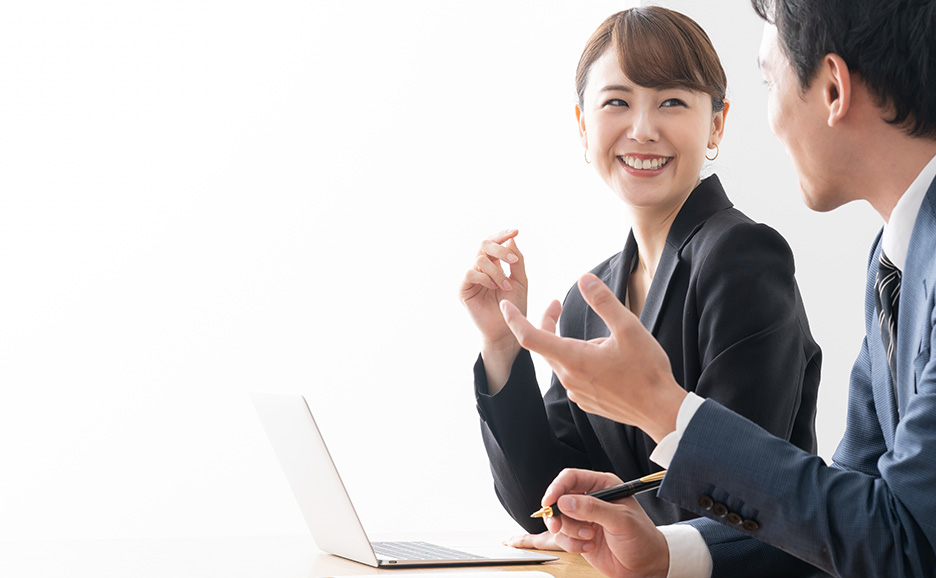 ノートパソコンの前で、笑顔の女性と身振り手振りで話す男性。