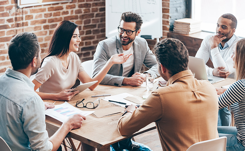 会議室でテーブルを囲み、笑顔で活発に議論するビジネスワーカーたち。