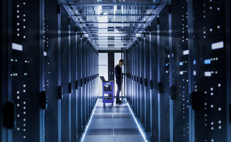 データセンターの通路でサーバーラックを操作する技術者。