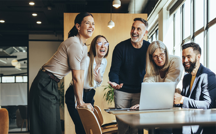 ノートパソコンを見ながら笑っている5人のビジネスパーソン。