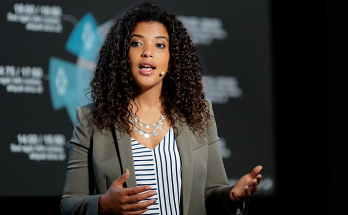 マイクをつけて身振り手振りで話す女性。