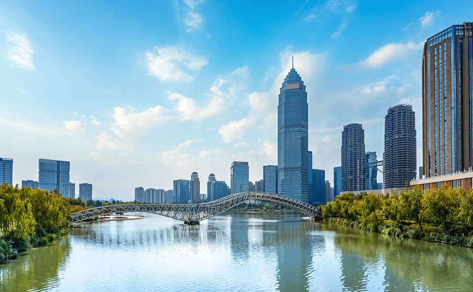 水路、橋、モダンな高層ビルが青空の下に広がる都市の風景。