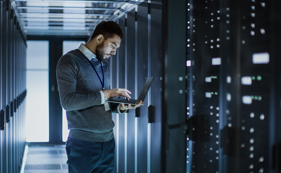 サーバー室でラップトップを操作するIT技術者。