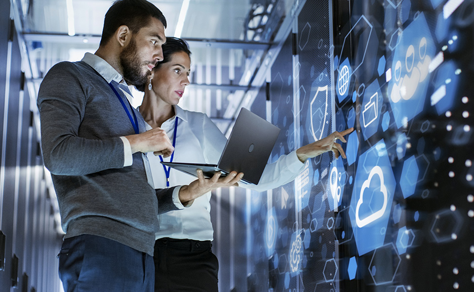 データセンターでノートPCを使い、VR画面を操作する2人のIT専門家。