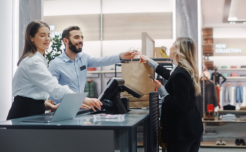 Two clerks dealing with a woman buying clothes at the counter