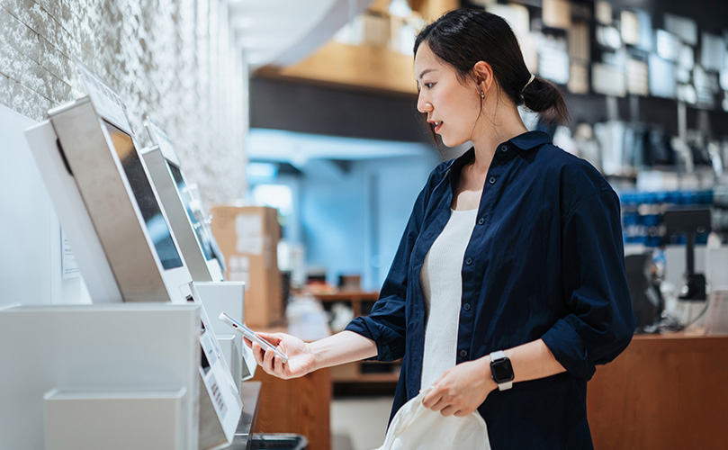 A woman paying for purchases at a store's self-checkout counter