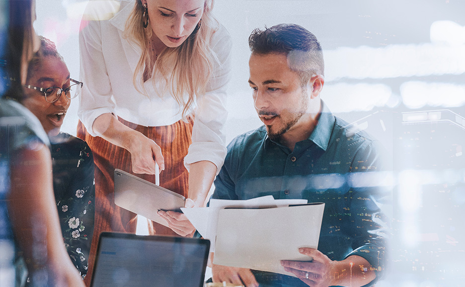 デバイスを見ながら打ち合わせをするプロジェクトメンバー