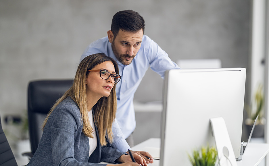 パソコンを見ながら会話する2人のビジネスパーソン