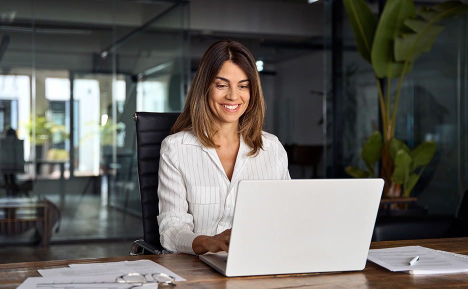 オフィスでノートパソコンを操作し、笑顔の女性。