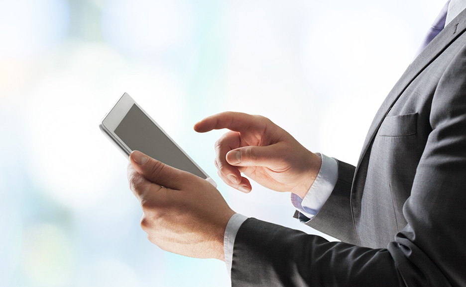 タブレットデバイスを操作するスーツ姿のビジネスマンの手元。