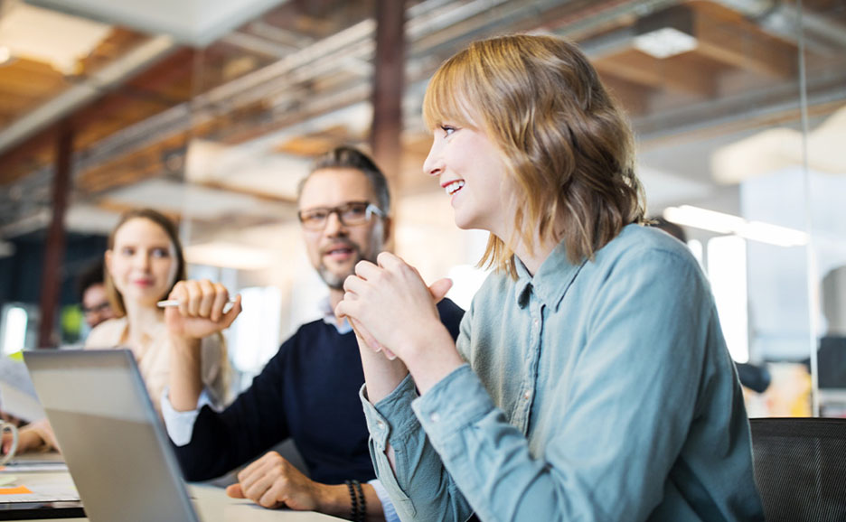 A woman in a cheerful meeting with her laptop unfolded
