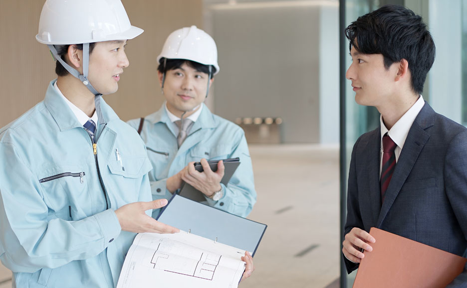 作業着の男性と打ち合わせをするビジネスマン
