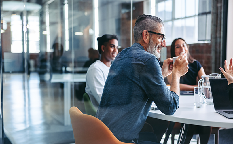 A team of professionals gathered around a table in an office, focused on a discussion or brainstorming session.