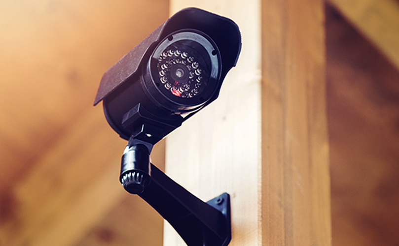 Mounted security camera on a wooden wall, providing surveillance for enhanced safety and monitoring.