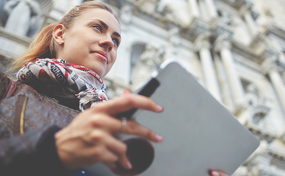 建物の前でタブレット持っている女性