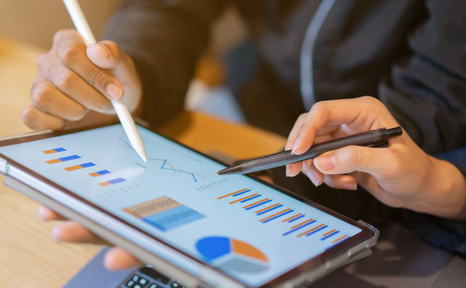 A person's hands analyzing data on a tablet