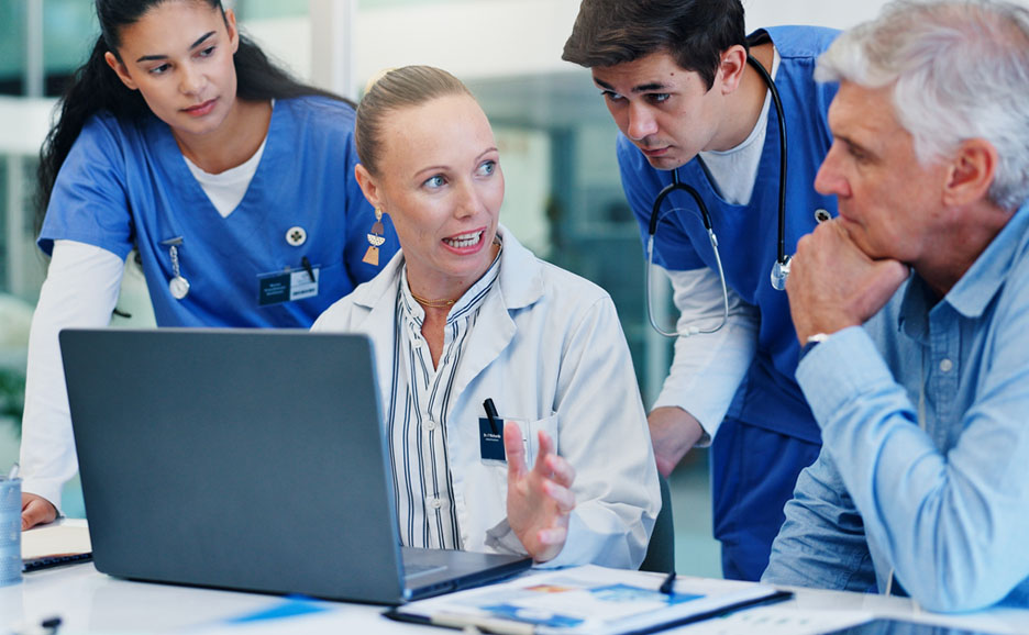 ノートパソコンを見ながら討論する医療スタッフ