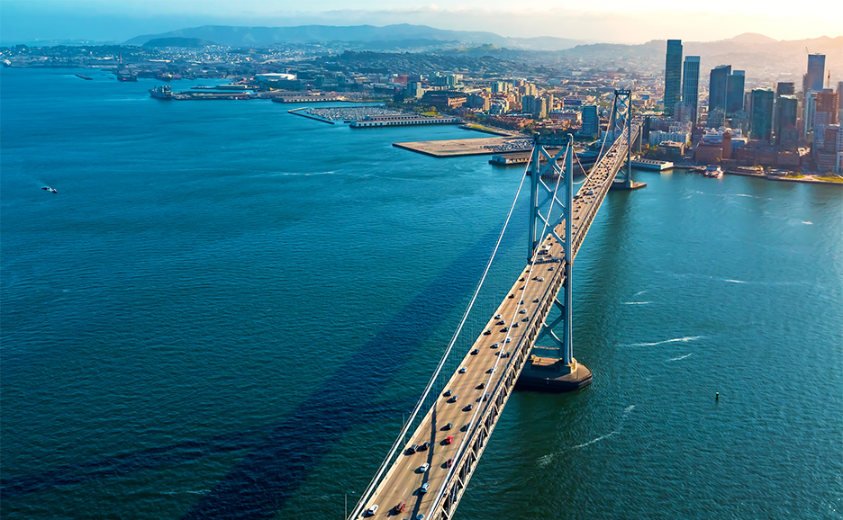 Cars pass over the bridge against the backdrop of the city and the sea.