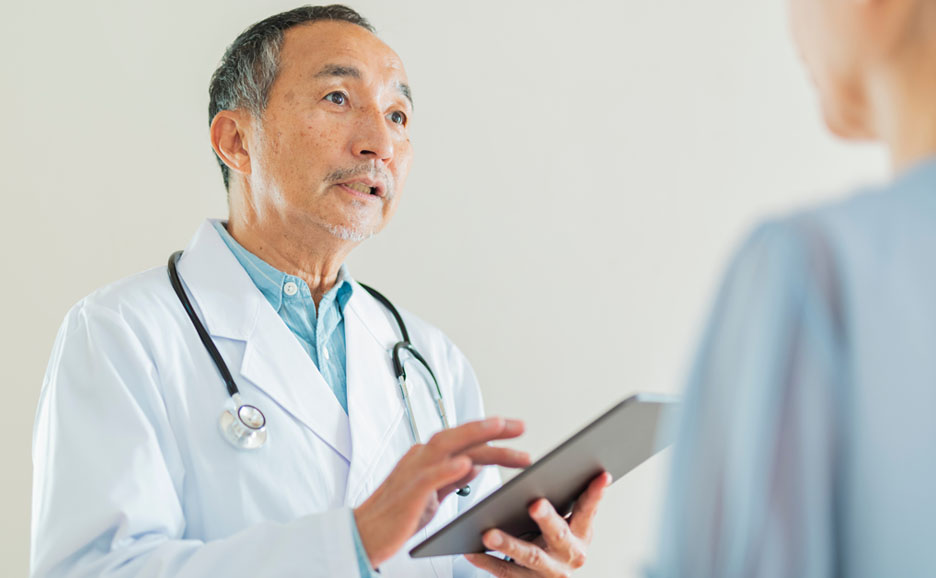 タブレットを操作しながら診断している医師