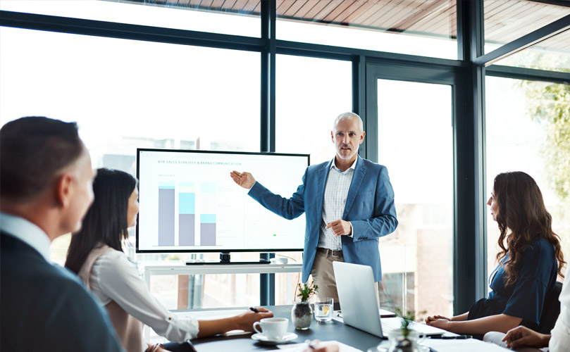 Company employees discussing business strategies with graphs and charts in a conference room.