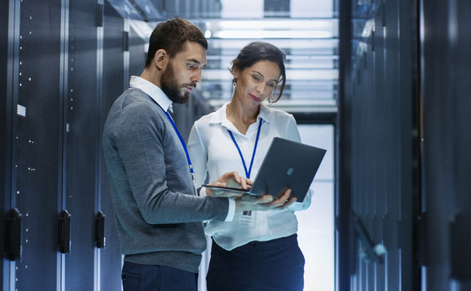 サーバールームでノートPCを見る男女