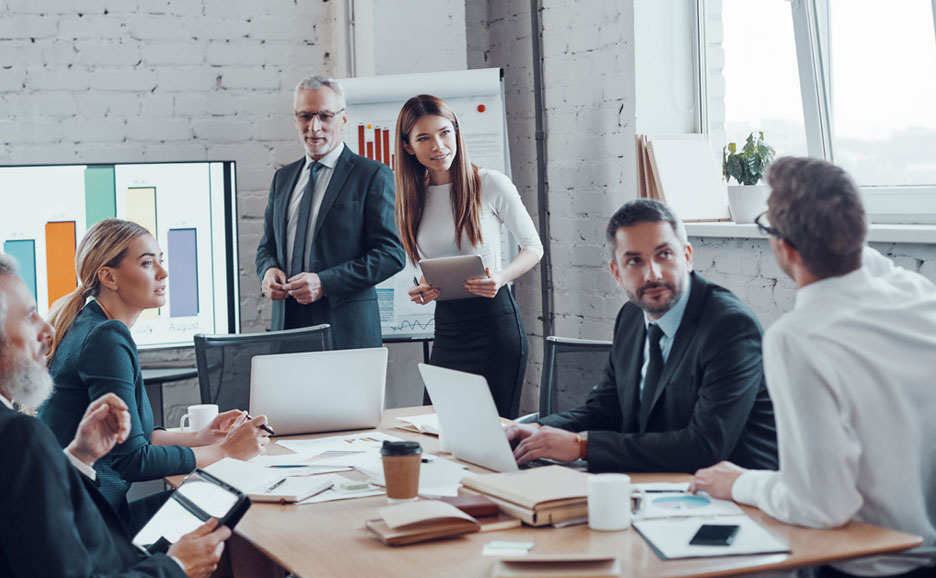 会議室でPCやタブレットを使い議論するビジネスパーソンたち