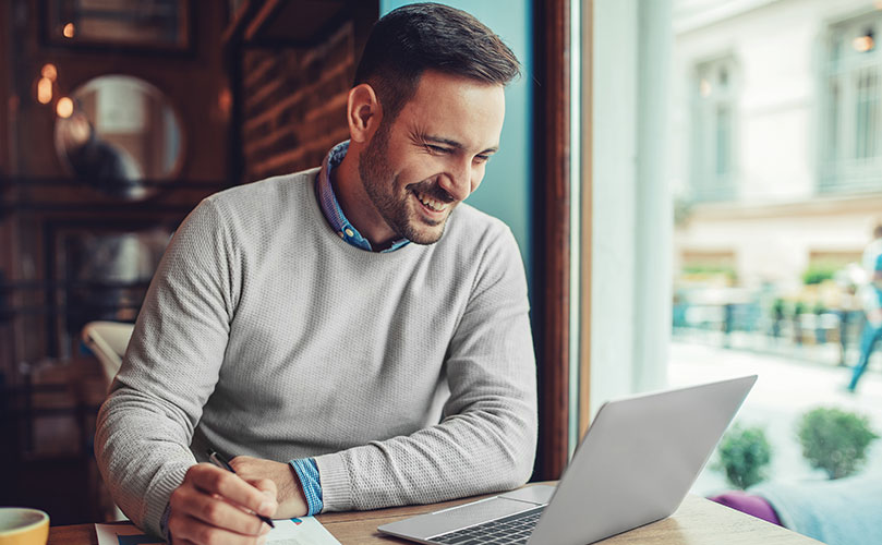Mann arbeitet an einem Laptop in einem Café