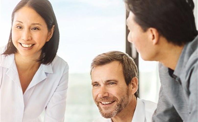 Three people engaged in conversation while seated around a table.
