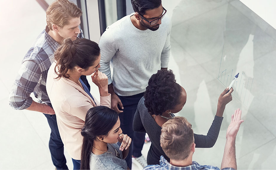 プロジェクトメンバー５名がホワイトボードを見ながら会話をしている