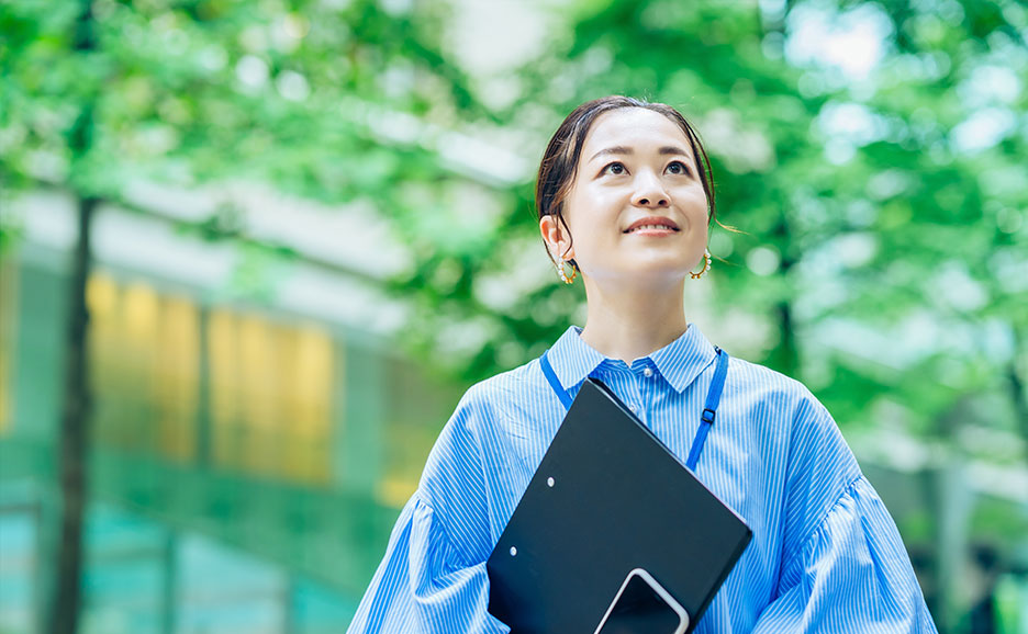 緑があるオフィス街で上を見ている女性