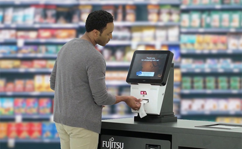 A man at a self-checkout machine, processing his grocery items in a supermarket.