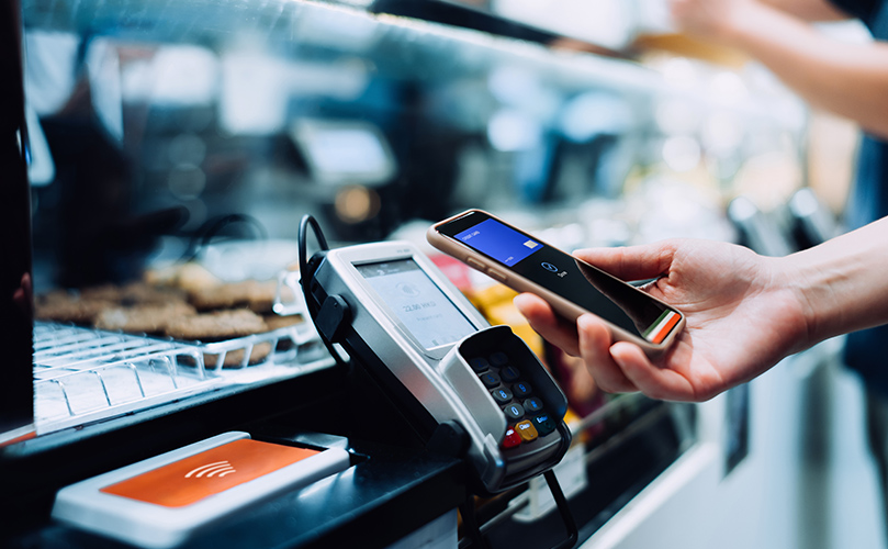 A person using a mobile phone to complete a payment transaction at a store.
