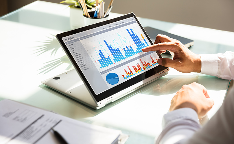 Individual using a laptop with a visible graph, likely analyzing trends or statistics.