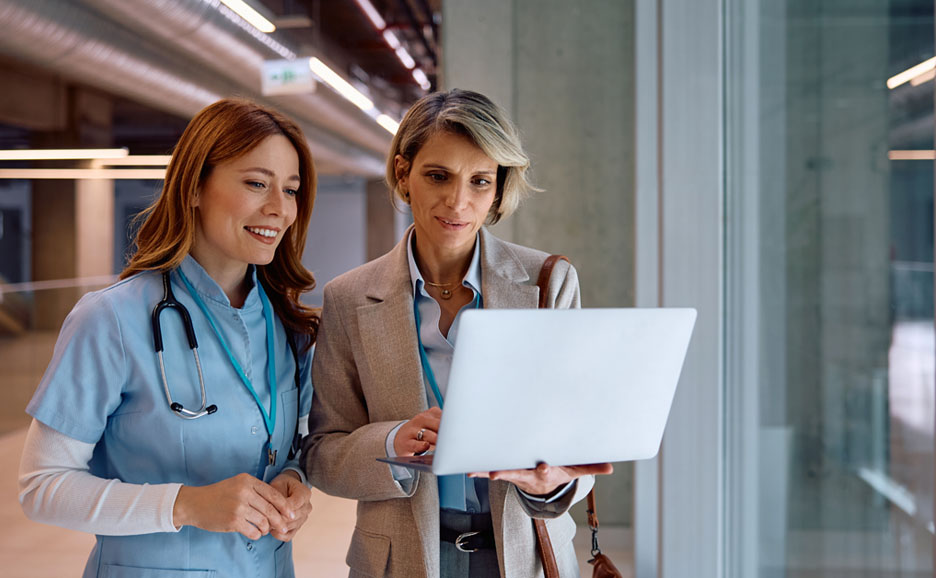 ノートパソコンを持った営業と医療従事者が会話をしている