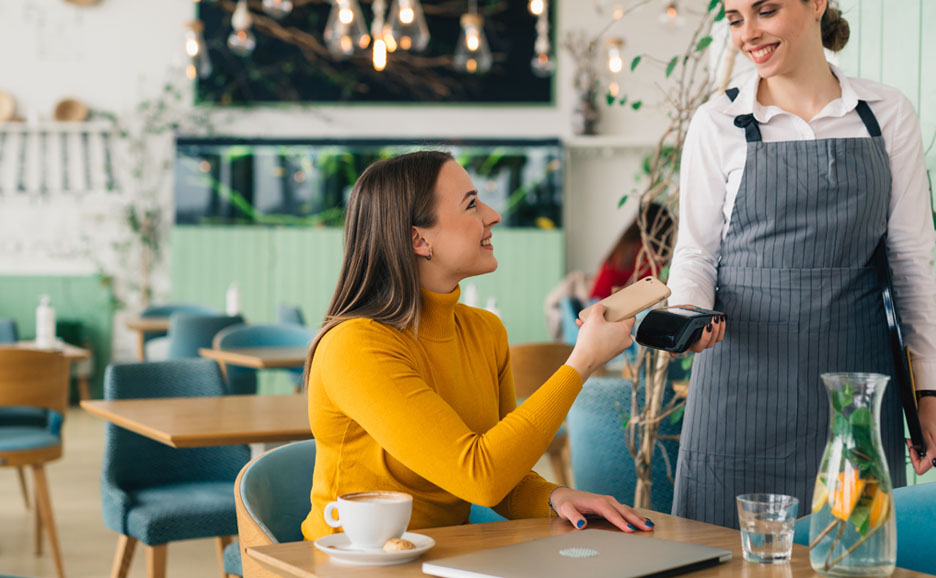 カフェの席で会計するお客の女性と従業員