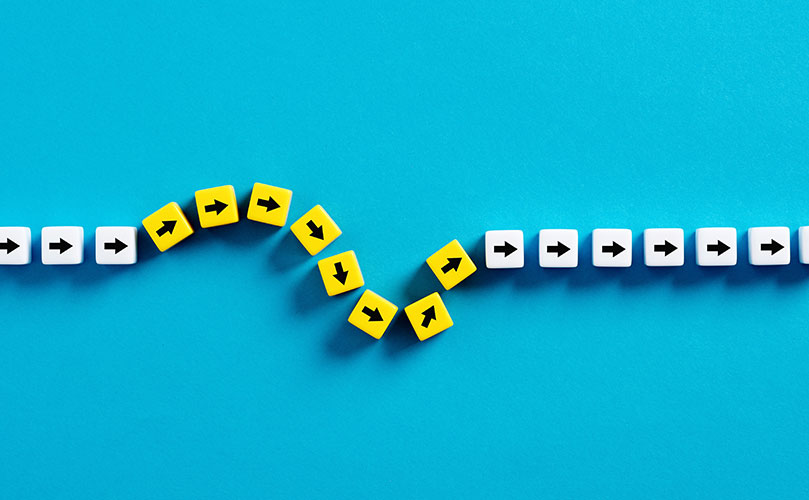 青い背景に並ぶ、方向転換する矢印ブロック。変化、適応を示す。