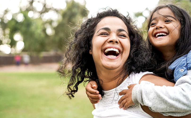 laughing together in the park with a child on their back