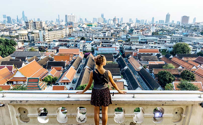 A woman is standing on a balcony looking down at the city