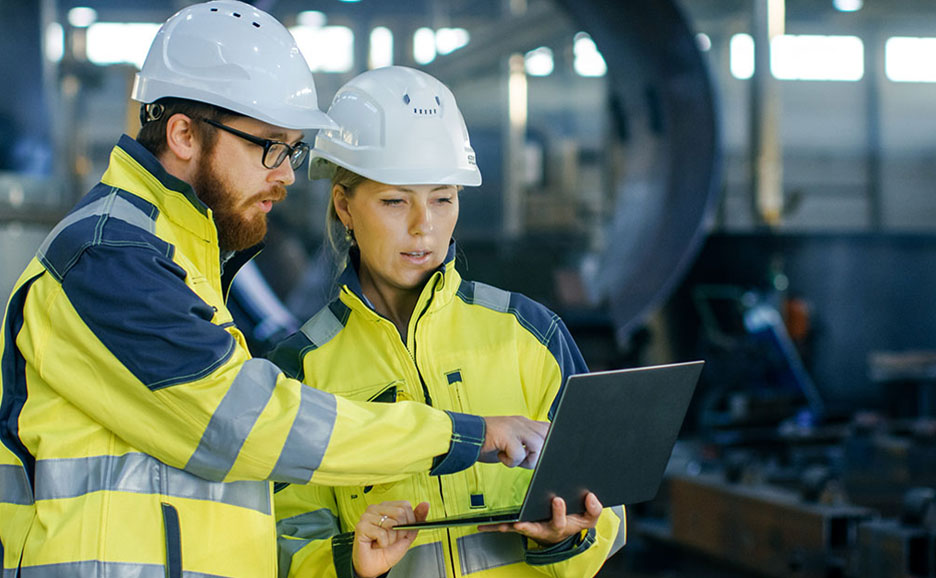 Male and female workers looking at a laptop in a factory