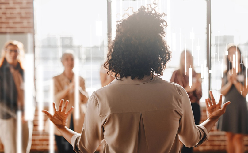 A woman stands confidently in front of a group of attentive people, engaging them with her presentation.