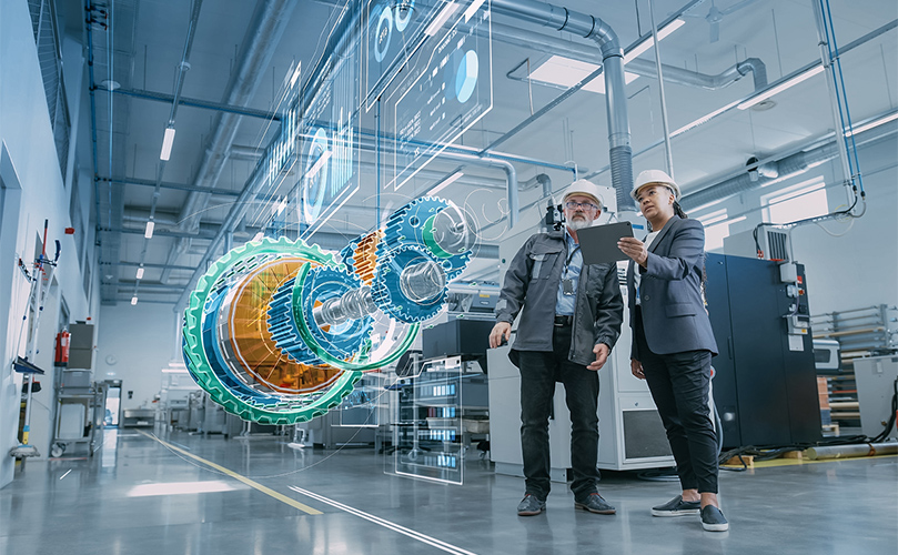 Two factory workers examining a tablet together, surrounded by machinery and equipment.  