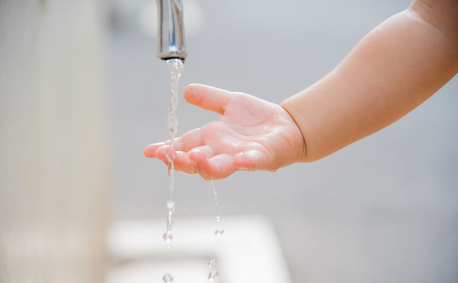蛇口から流れる水を触る子供の手