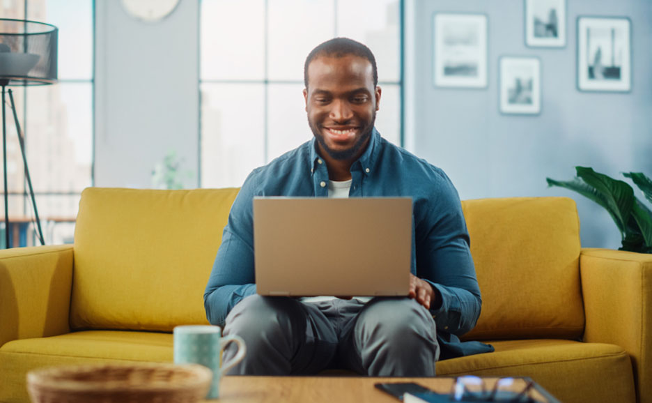 黄色いソファーの上でノートパソコン作業をしている男性