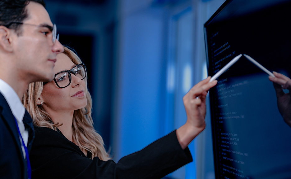 モニタを指し示しながら会話をする男女