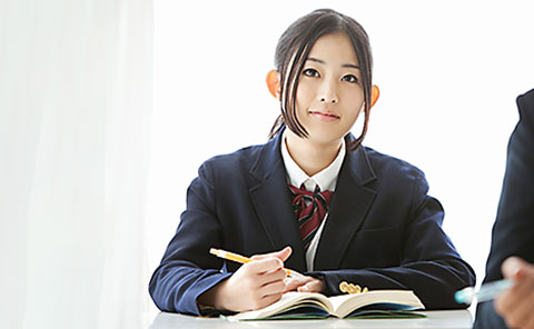 机に向かい、熱心に勉強する女子学生。